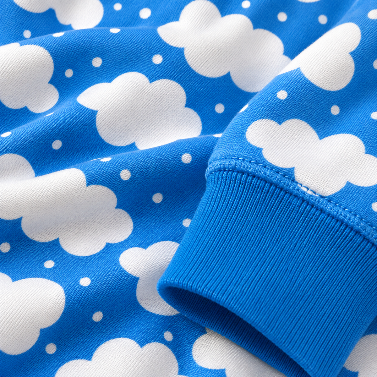 Close-up of a blue ribbed cuff with a white cloud and small dot pattern on the fabric.