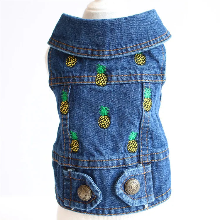 A blue denim vest for small pets, featuring embroidered pineapple motifs on the front, displayed on a white mannequin torso against a white background.