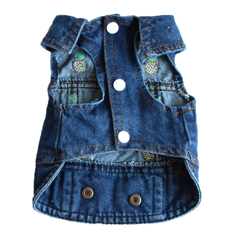 A blue denim pet vest with white snap buttons, decorative pockets, and embroidered pineapple details, shown on a plain white background.