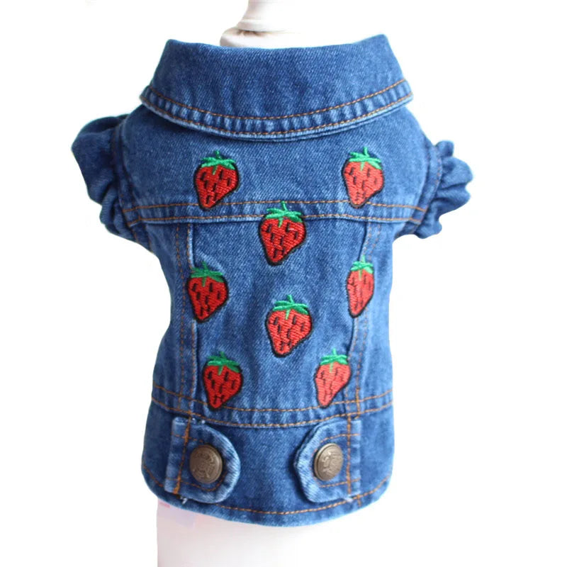 A blue denim pet jacket with embroidered red strawberries on the front, displayed on a white mannequin torso against a white background.