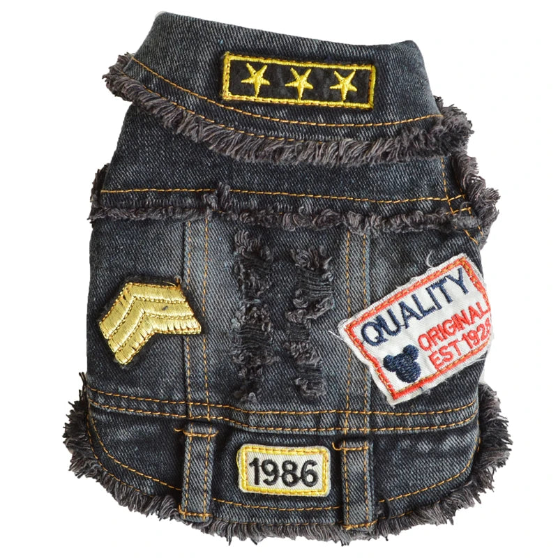 A small dark gray denim-style vest or jacket with distressed frayed edges, yellow contrast stitching, embroidered patches, and decorative details, shown on a plain white background.