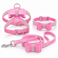 Pink dog harness, collar, and leash set with bow and rhinestone details on a white background