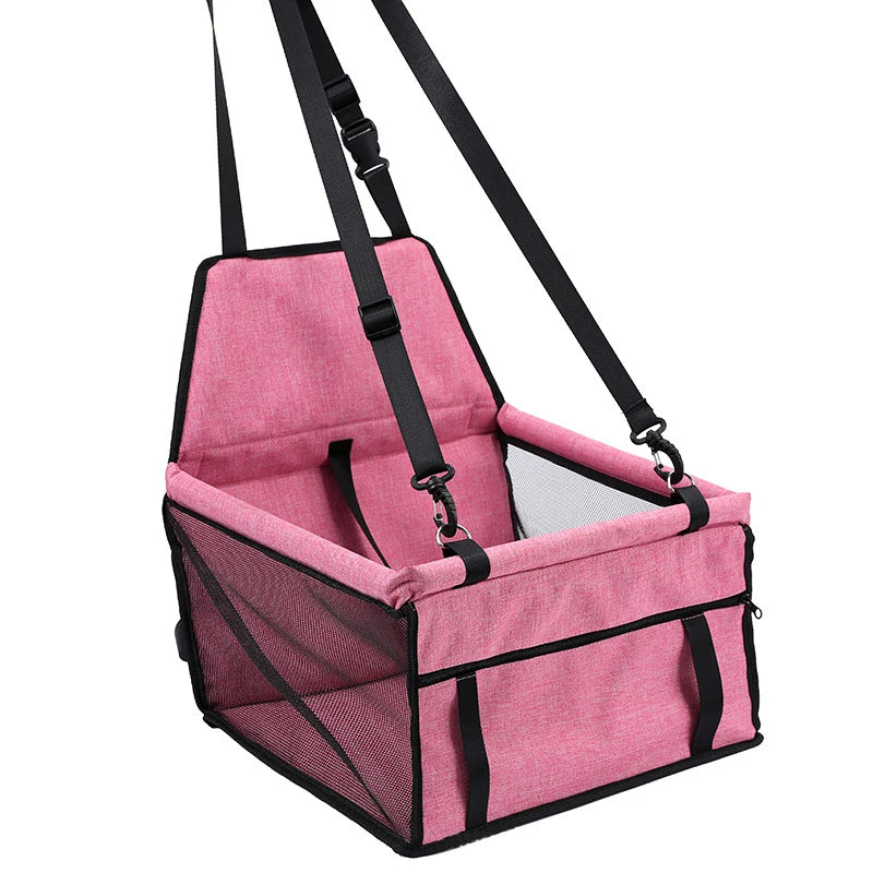 Pink pet car seat with black straps on a white background